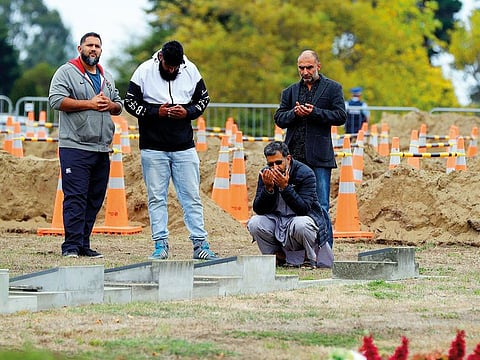 Four men pause for prayer at a Muslim cemetery in Christchurch, New Zealand.