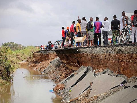 Locals stand beside a damaged section of the road between Beira and Chimoio in Nhamatanda district, central Mozambique, on March 19, 2019, after the area was hit by the Cyclone Idai.