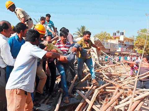 Rescue workers and members of the public carry a survivor after he was found under the rubble of an under-construction multi-storey building that collapsed in Dharwad district of Karnataka some 700 kilometres north of Bangalore on March 19, 2019.