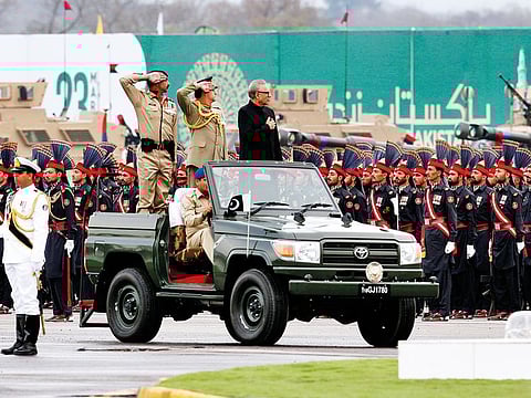Pakistan's President Arif Alvi, in black suit on a military vehicle, reviews a military parade to mark Pakistan National Day, in Islamabad, on Saturday. 