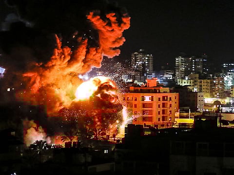 Fire and smoke billow above buildings in Gaza City during Israeli strikes.