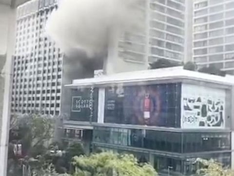 Smoke billows along a street after a fire broke out at Grand Hyatt hotel in Orchard Road, Singapore, March 27, 2019, in this still image taken from a video from social media. 