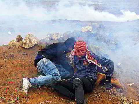Palestinian demonstrators take cover from the Israeli regime’s gunfire and tear gas during Saturday’s protest.