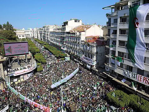People carry national flags and banners during a protest to demand the resignation of President Abdelaziz Bouteflika, in Algiers, onMarch 29, 2019. 