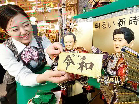 A shop worker arranges Japanese traditional dolls depicting Japanese Chief Cabinet Secretary Yoshihide Suga, left, and Japanese Prime Minister Shinzo Abe, right, holding the new era name "Reiwa" at Kyugetsu, a Japanese doll company, in Tokyo.