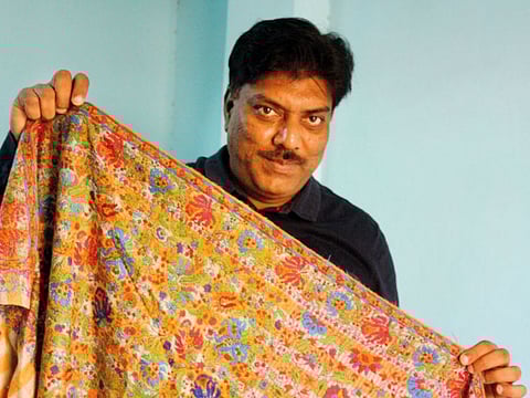 Intekhab Ahmad displaying a jamavar shawl that has been flawlessly restored. 