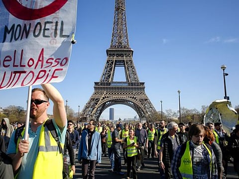 French yellow vest protesters, backdropped by the Eiffel Tower are rallying to support an older woman activist injured in a confrontation with police, Saturday, March 30, 2019, in Paris. 