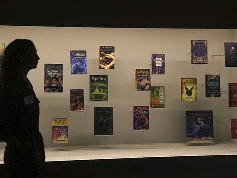 A member of British Library staff poses for a picture with Harry Potter books published in several languages at the "Harry Potter - A Histroy of Magic" exhibition at the British Library, in London, Wednesday Oct. 18, 2017, 2017.