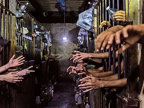 Prisoners beg for food and water at their cells in a police station. Many said they had regular jobs but turned to crime because of the impossibility of bringing food home.