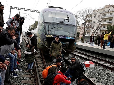 Migrants and refugees, who say that they seek to travel onward to northern Europe, sit on railway tracks during a protest at main railway station in Athens, Greece