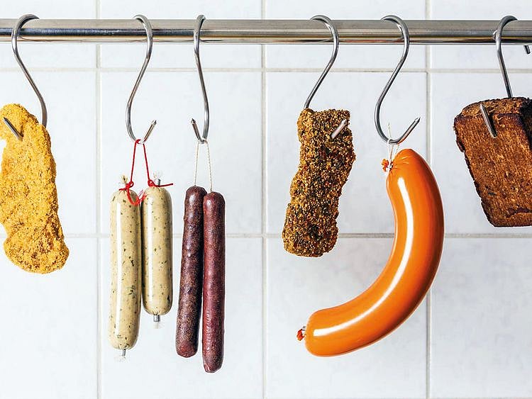 Vegan and vegetarian sausages and steaks hanging on hooks.
