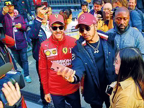 Mercedes driver Lewis Hamilton of Britain, right, takes a smartphone selfie with Ferrari driver Sebastian Vettel of Germany after attending an autograph session at the Shanghai International Circuit ahead of the Chinese Formula One Grand Prix in Shanghai, China.