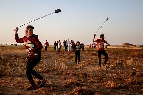 A Palestinian uses a slingshot during a demonstration near the border with Israel, east of Khan Yunis in the southern Gaza Strip, on April 12, 2019. 