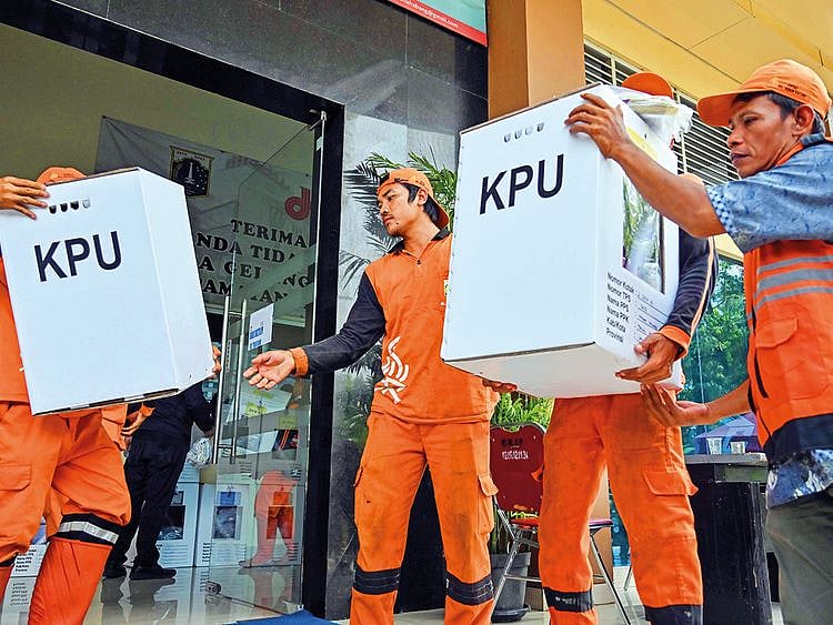 Officials carry vote materials during the distribution in Jakarta