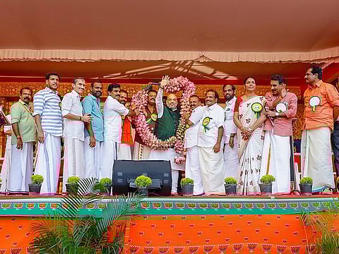 BJP National President Amit Shah greets supporters after being garlanded during his election campaign for Lok Sabha polls, in Thrissur.