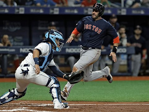 Boston Red Sox's J.D. Martinez, right, scores around Tampa Bay Rays catcher Michael Perez on an RBI-double by Rafael Devers during the fifth inning of a baseball game Friday, April 19, 2019, in St. Petersburg, Florida.