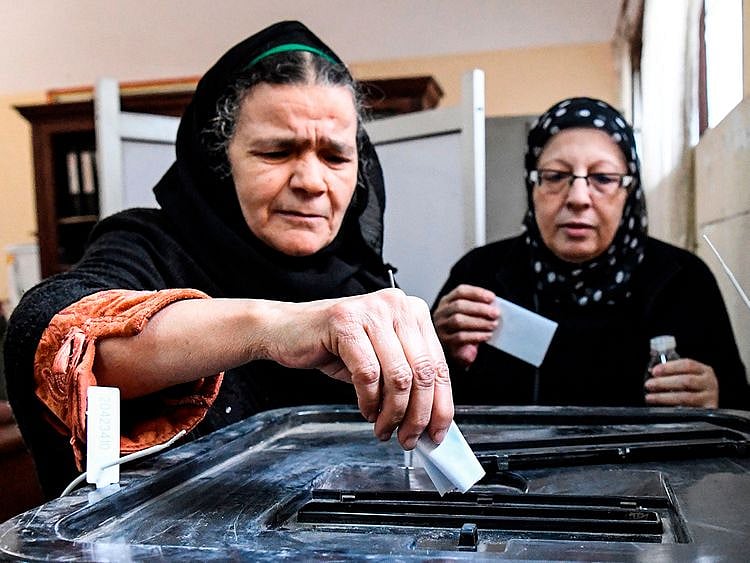 Egyptian women cast their ballots in a box
