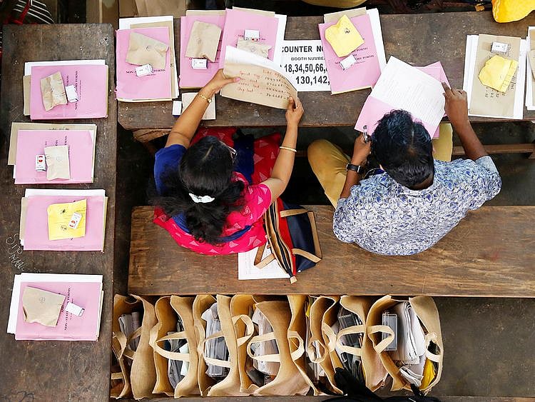 Election officials sit next to election materials
