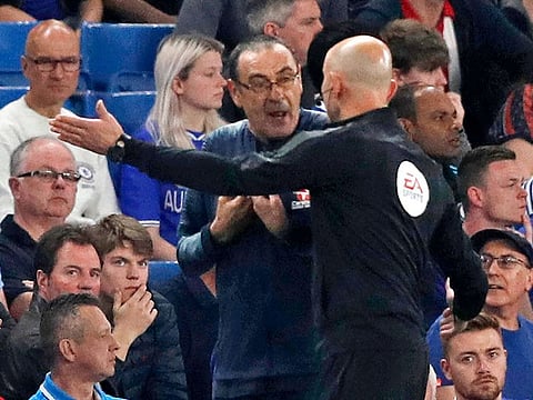 In this file photo taken on April 22, 2019 Fourth official Roger East (R) directs Chelsea's head coach Maurizio Sarri from the technical area during the English Premier League football match between Chelsea and Burnley at Stamford Bridge in London.  