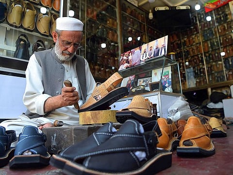 Chacha Noor Din, the owner of a string of shoe stores, makes a pair of sandals at his shop in Peshawar.