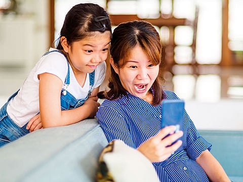 A mother enjoys free time with her daughter at home.