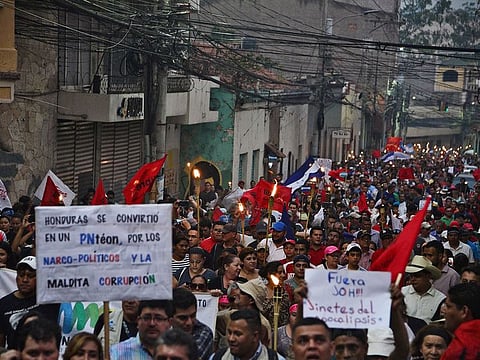 Hondurans demonstrate with torches against the approval of education and health bills demanding the resignation of Honduran President Juan Orlando Hernandez in Tegucigalpa on April 26, 2019. 