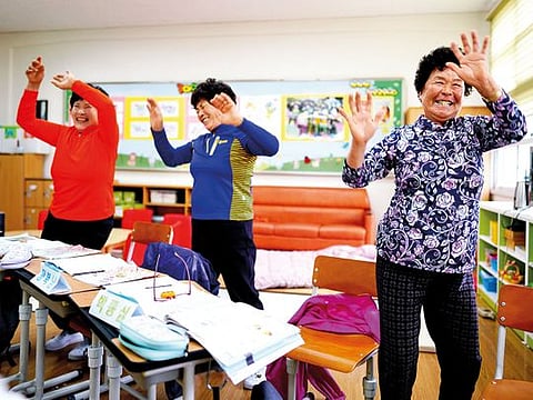 From left: Hwang Wol-geum, 70, Kim Mae-ye, 64, and Park Jong-sim, 75, dance to a children’s song at Daegu Elementary, in Gangjin County, South Korea.