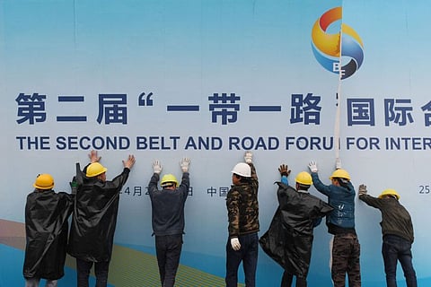 Workers take down a Belt and Road Forum panel outside the venue of the forum in Beijing on April 27, 2019.