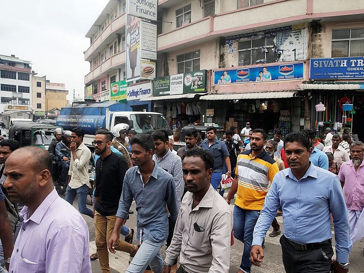 People cross a street in central Colombo