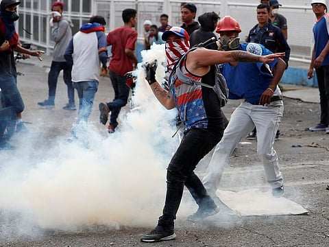 A demonstrator throws back a tear gas canister during clashes with government security forces in Caracas, Venezuela April 30, 2019.