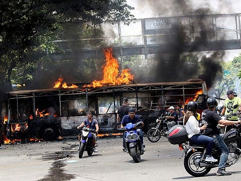 People drive their motorcycles near a burnt bus during anti-government protests, in Caracas, Venezuela April 30, 2019.