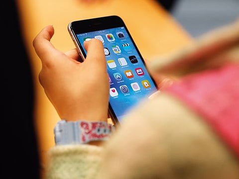 A child holds an Apple iPhone 6S smartphone