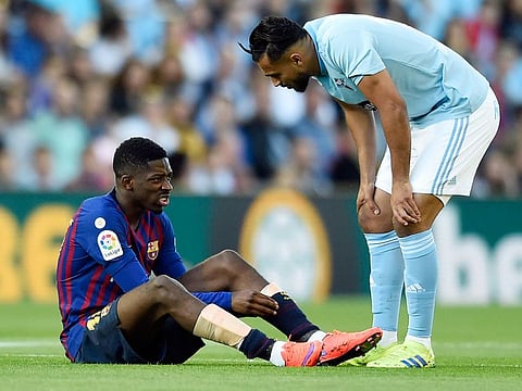Celta Vigo's midfielder Sofiane Boufal (right) checks on Barcelona's forward Ousmane Dembele after resulting injured during the Spanish league football match between RC Celta de Vigo and FC Barcelona at the Balaidos stadium in Vigo on May 4, 2019. 