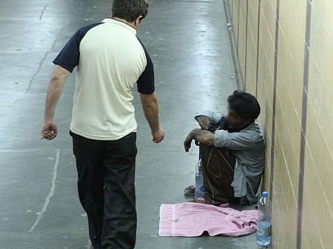 A man gives money to a beggar in an underpass. Police have warned the public about the continued menace posed by beggars as they deploy various tricks to seek sympathy.