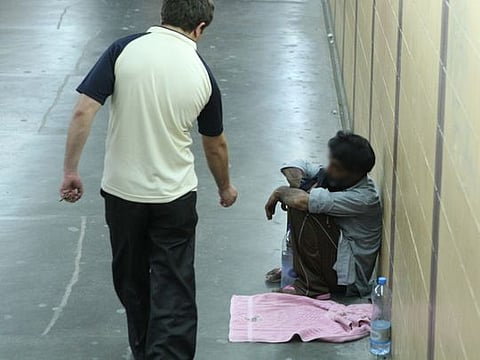 A man gives money to a beggar in an underpass. Police have warned the public about the continued menace posed by beggars as they deploy various tricks to seek sympathy.