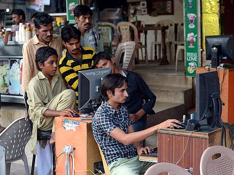 Pakistani vendors use computers to upload music and video files onto their client's mobile phones at a market in Faisalabad. 