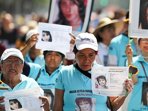 People carry images of people who were disappeared, during a Mother's Day march in Mexico City, Friday, May 10, 2019. 