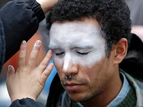 A man, who declined to be identified, has his face painted to represent efforts to defeat facial recognition during a protest at Amazon headquarters over the company's facial recognition system, "Rekognition," in Seattle. 