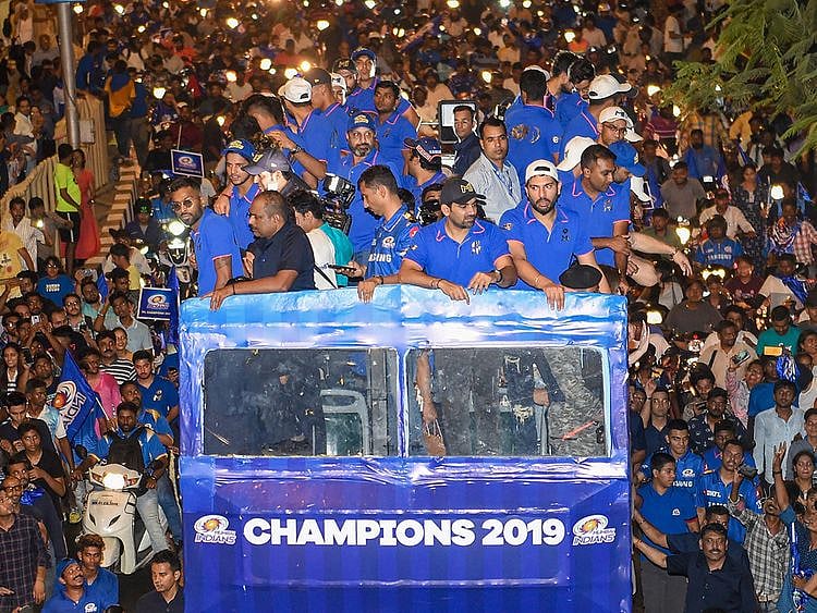 Mumbai Indians (MI) players travel atop an open bus