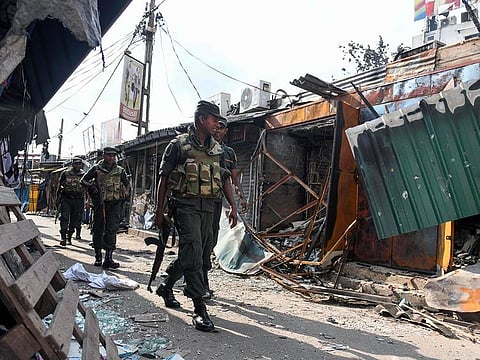 Sri Lankan soldiers walk past a damaged shop after a mob attack in Minuwangoda.