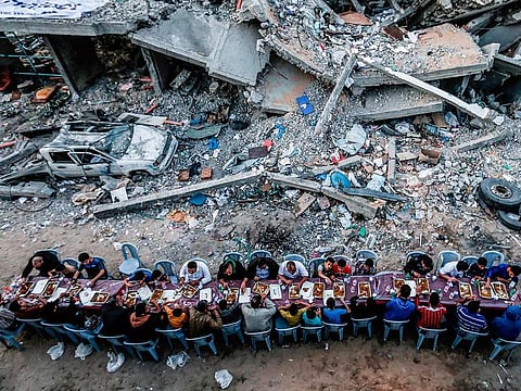 Palestinian families break their fast next to a destroyed building during recent confrontation between Hamas and Israel, in Gaza Strip