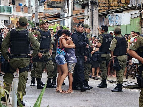 Residents mourn surrounded by police officers outside a bar as corpses are removed after a shooting, in Belem, Para state, Brazil on May 19, 2019.
