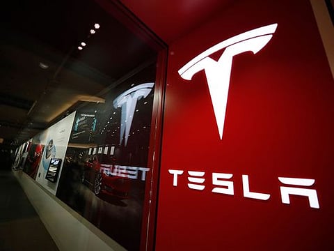 A sign bearing the company logo is displayed outside a Tesla store in Cherry Creek Mall in Denver