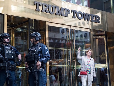 Heavily armed police officers stand guard as a tourist poses for a photo outside Trump Tower, Thursday, May 16, 2019, in New York. 