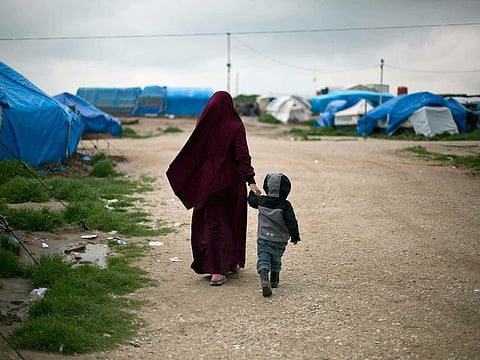 In this March 27, 2019, file photo, Samira, a Belgian national married to a French Islamic State member, Karam Al Harchaoui, walks with their son at Camp Roj in north Syria.
