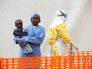 Mwamini Kahindo, an Ebola survivor working as a caregiver to babies who are confirmed Ebola cases, holds an infant outside the red zone at the Ebola treatment centre in Butembo, Democratic Republic of Congo, March 25, 2019.