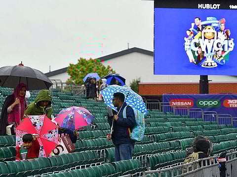 Cricket fans huddle under umbrellas as rain delays start of play at a 2019 Cricket World Cup game. The Duckworth-Lewis method has synonymous with rain-affected games in contemporary cricket.