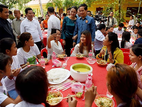 Phnom Penh governor Khuong Sreng (top centre) posses for a selfie with a woman as people eat noodles during a noodles feast at a pagoda in Phnom Penh on June 9, 2019. 