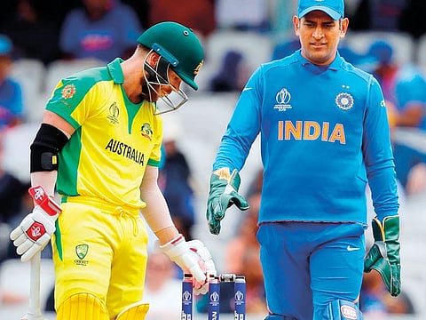 Australia’s David Warner (C) and India’s Mahendra Singh Dhoni look on after the ball touched his stumps but did not dislodge the bails during the India v Australia match.