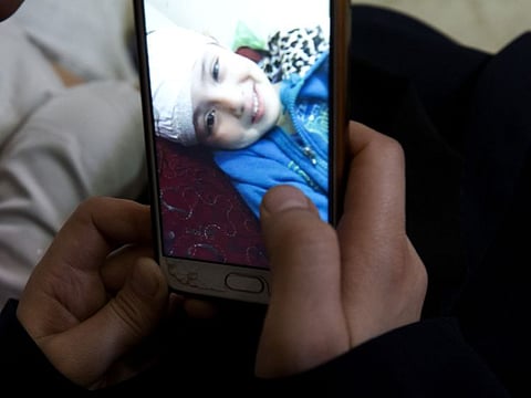 In this May 27, 2019, photo, Muna Awad, mother of 5-year-old Aisha a-Lulu, shows her photo while Aisha is in an Occupied Jerusalem hospital, at the family home in Burij refugee camp, central Gaza Strip. 